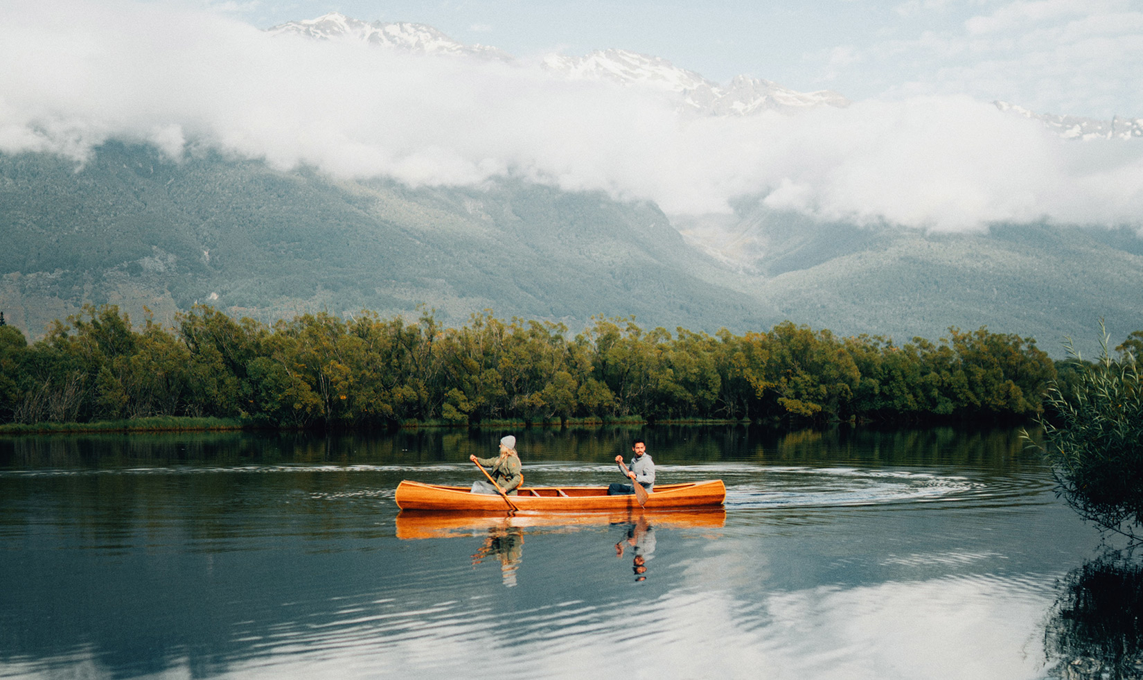 Man and woman paddling canoe in the mountains